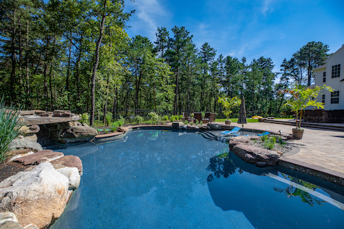 Custom-built, in-ground pool with rock formations and a curved platform. 