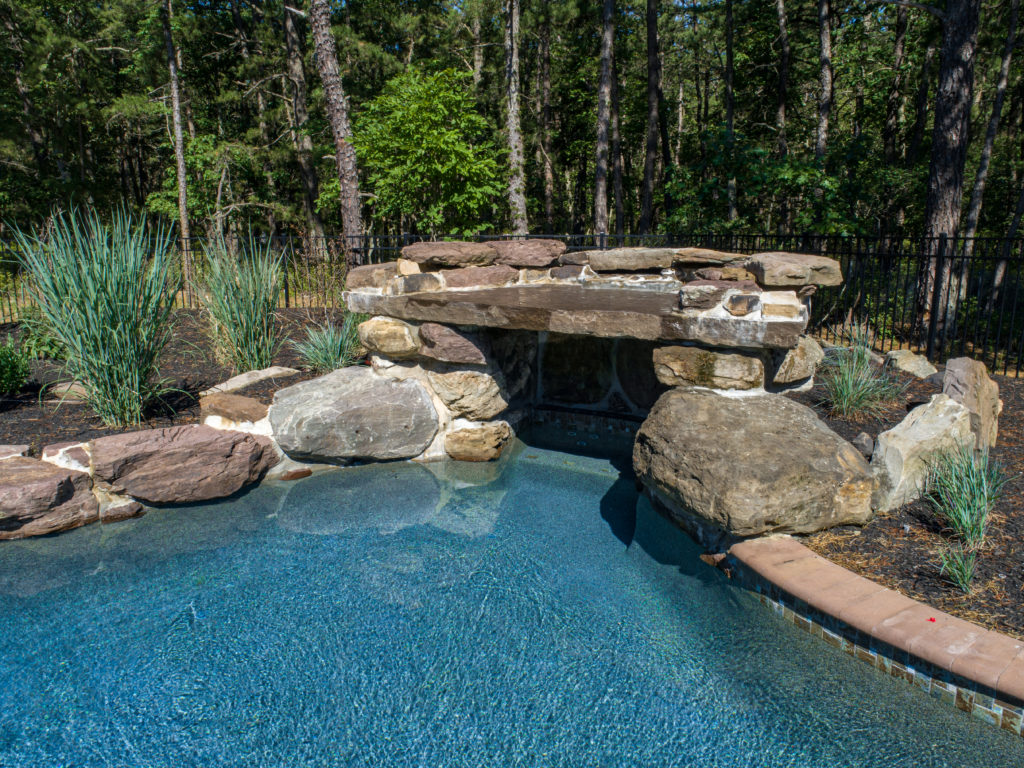 View of grotto feature in pool made of stone. 