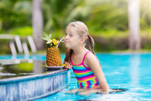 Child drinking juice in swimming pool bar. 