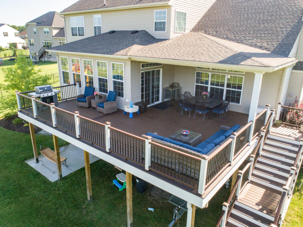 Raised, attached deck featuring blue furniture, a grill, and a dining table. 