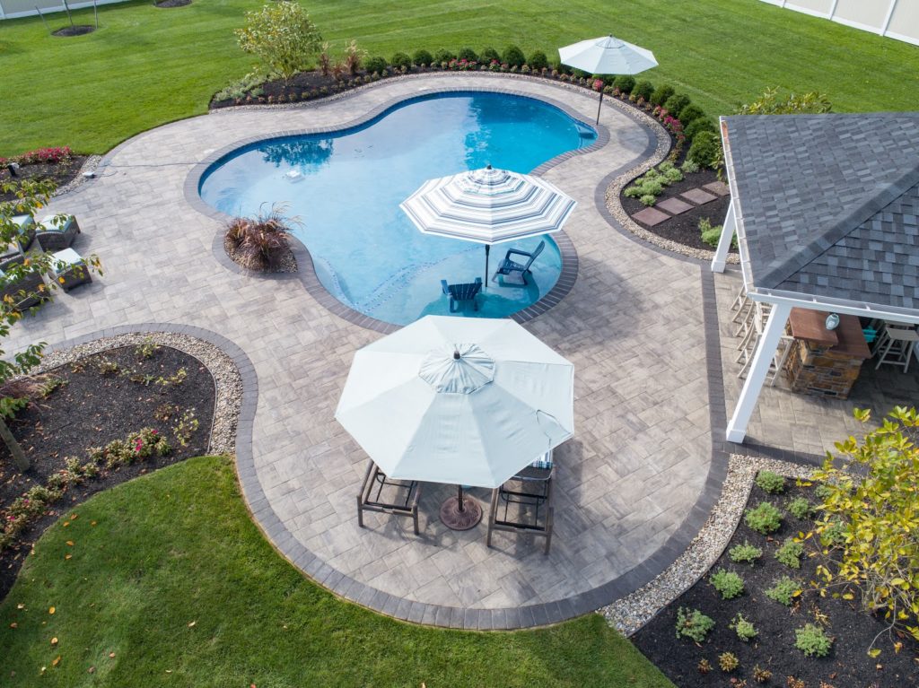 Aerial view of custom, in-ground pool featuring pool umbrellas and lounge chairs.