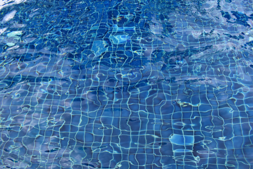 Close up of deep blue, checkered vinyl liner in a pool with wavy water. 